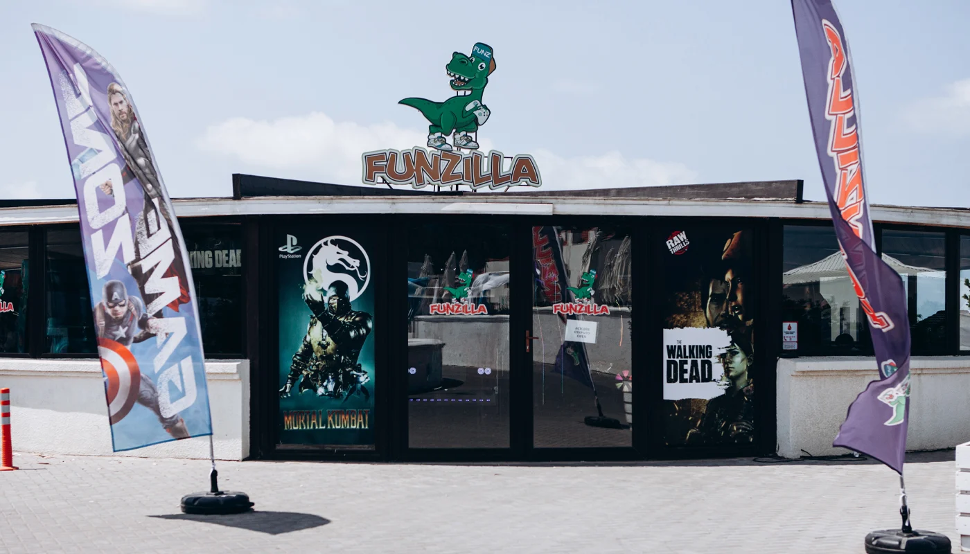 Вход в Funzilla: динозавр и надпись FUNZILLA на крыше, флаги у дверей